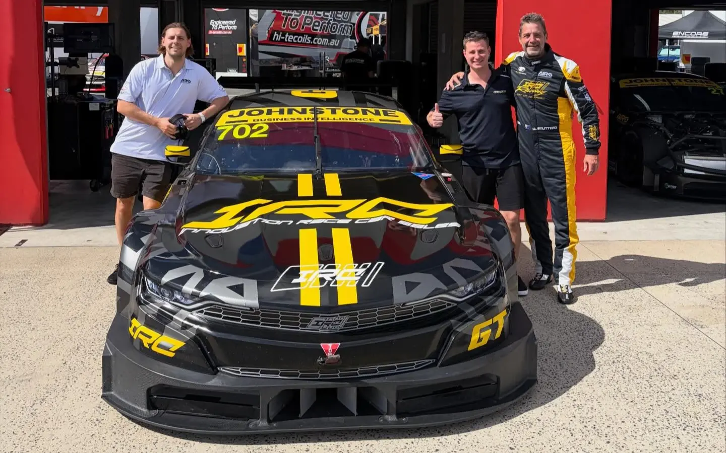 Johnstone Business Intelligence team with the AIRC #702 race car in the pit garage
